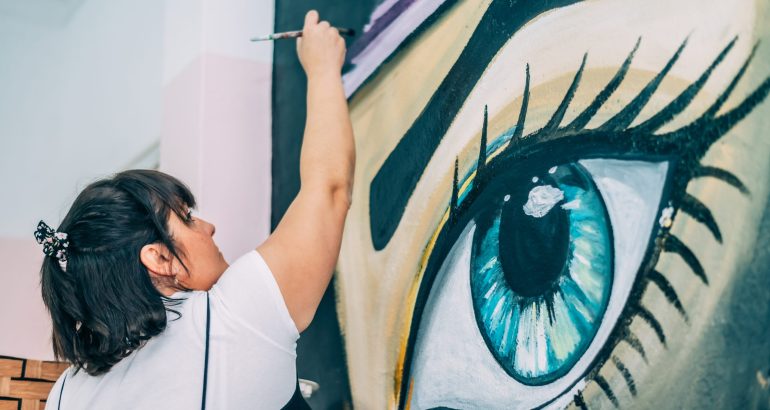 Woman artist painting eye mural in studio